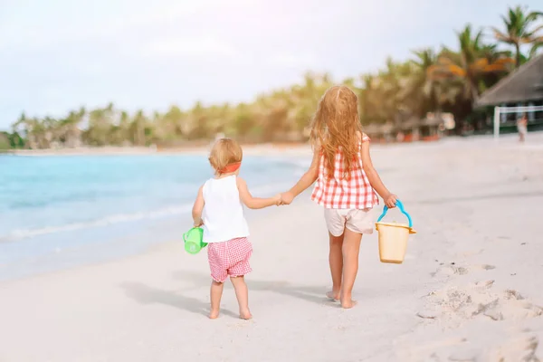 Malé šťastné zábavné dívky mají spoustu zábavy na tropické pláži hrát spolu. — Stock fotografie
