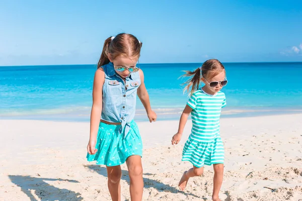 Pieni onnellinen hauskoja tyttöjä on hauskaa trooppisella rannalla leikkii yhdessä. — kuvapankkivalokuva