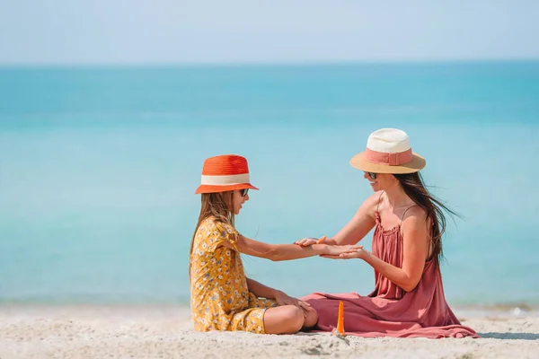 Молода мама застосовує сонячний крем для дочки ніс на пляжі. Захист від сонця — стокове фото