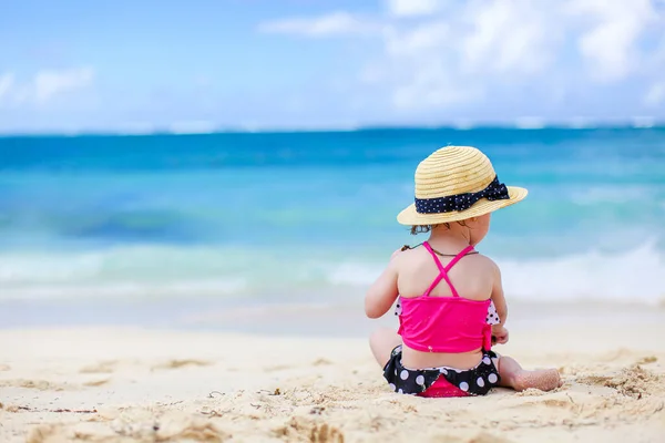 Маленькая девочка на тропическом белом пляже строит замок из песка — стоковое фото