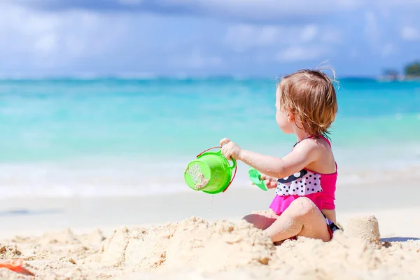 Liten flicka på tropisk vit strand gör sand slott — Stockfoto