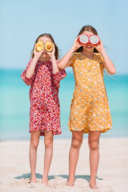 Küçük mutlu komik kızlar tropikal plajda birlikte oynarken çok eğlenirler..