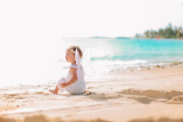 Mooi jong meisje dragen engel vleugels op het strand — Stockfoto