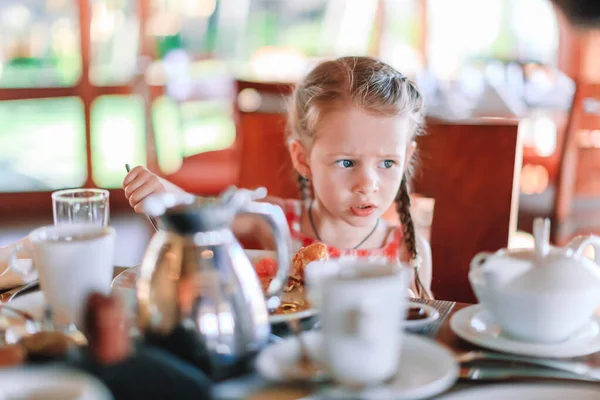 Imádnivaló kislány a kávézóban reggelizik. — Stock Fotó