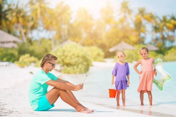 Crianças tristes esperando seu pai trabalhando com laptop para nadar e se divertir na praia — Fotografia de Stock