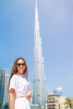 Dubai 'de arka planda gökdelenle yürüyen mutlu bir kadın..