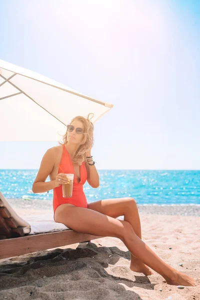 Junge Frau im Badeanzug mit Cocktailglas am weißen Strand auf Sonnenliege — Stockfoto