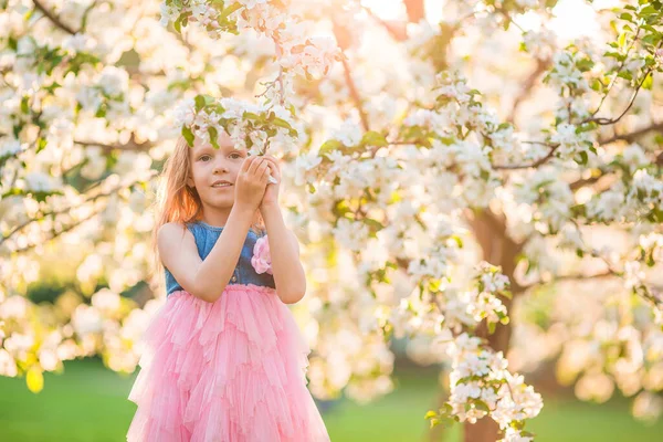 Imádnivaló kislány a virágzó almakertben, gyönyörű tavaszi napon. — Stock Fotó