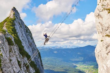 Yaz aylarında ferrata ile Donnerkogel 'i ara, çapraz merdivene tırmanırken zafer işareti gösteren bir adamla. Cennete giden merdiven kavramı.