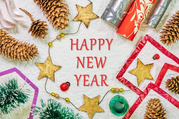 Happy New Year - Winter composition with spruce cones, wrapping paper, star string, and ribbons, on white background with geometric shaped frames.