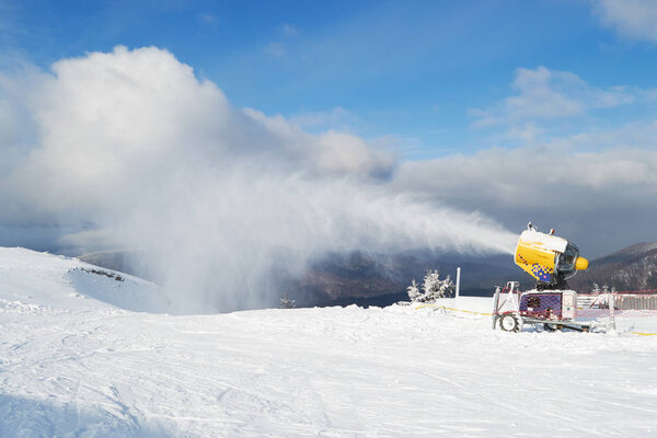 Snow cannon machine blowing artificial snow on Azuga ski domain, Prahova Valley region, Romania, during the Winter low season, due to the lack of natural snow.