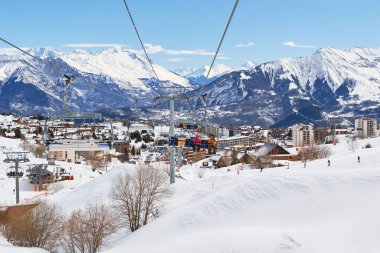 La Toussuire dağ köyü Les Sybelles kayak sahasında hareket halindeki bir teleferikten görüldü. Güneşli bir günde kış manzarası.