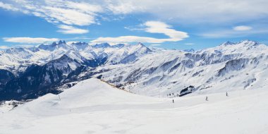 Les Sybelles kayak pistleri ve etrafındaki beyaz dağ tepeleri güneşli bir kış gününde Fransız Alplerinde panorama.