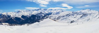 Fransa 'da Les Sybelles kayak bölgesi. Güneşli bir günde, yamaçları, kayakçıları ve dağ zirveleri olan bir panorama..