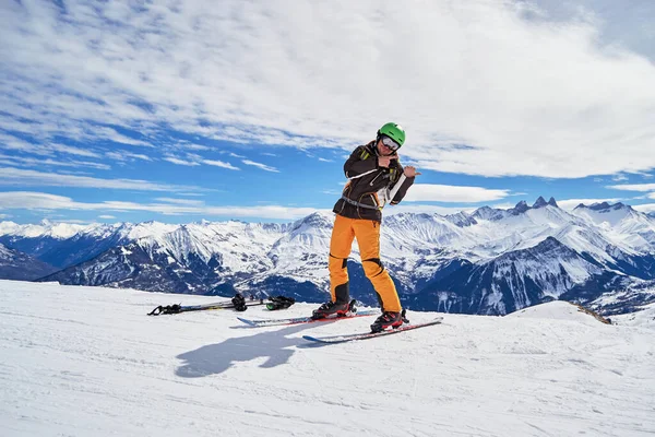 Glücklicher Mann auf Skiern, die im Rücken auf die Gipfel der Aaiguilles d 'arves in den französischen Alpen zeigen, sichtbar von einem hohen Aussichtspunkt auf den Skipisten des Les Sybelles Resort, Frankreich, an einem sonnigen Wintertag. — Stockfoto