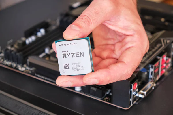 Mężczyzna ręka gospodarstwa Amd Ryzen 3700x Cpu powyżej a moherboard część a zwyczaj Pc budować. — Zdjęcie stockowe