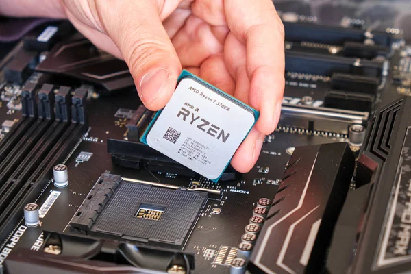 AMD Ryzen 3700X CPU em dedos técnicos, acima de uma placa-mãe, parte de uma construção de PC personalizado . — Fotografia de Stock