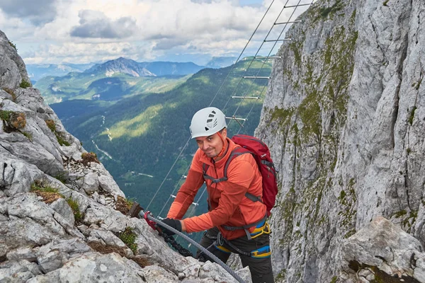 Ferrata Intersport, Donnerkogel Dağı, Avusturya üzerinden halat değiştirirken kameraya doğru göz kırpan tırmanıcı. — Stok fotoğraf