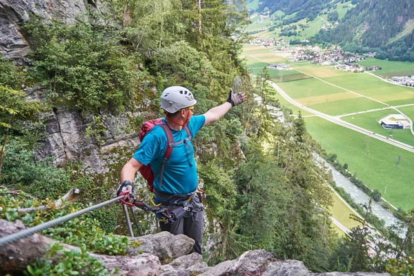Человек, указывающий рукой на долину Циллерталь, Австрия, с высоты по дороге через Феррату, называемой Пфайлшпитцванд, недалеко от Майрхофена. . — стоковое фото