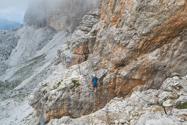 Tourist crossing a suspended wire bridge on via ferrata Cesare Piazzetta, στο δρόμο μέχρι την κορυφή Piz Boe, σε μια καλοκαιρινή περιοδεία περιπέτειας στα βουνά Δολομίτες, Ιταλία. — Φωτογραφία Αρχείου