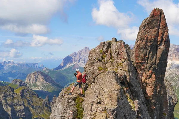 Fotógrafo de aventura olhando ao redor de um pequeno cume na via ferrata Delle Trincee, em Dolomites montanhas, Itália, em um dia ensolarado. Formações rochosas pontiagudas . — Fotografia de Stock