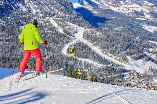 Kayakçı, İtalya 'nın Dolomites kentindeki La Villa köyünün yukarısında kırmızı bir kayağa atlamaya hazırlanıyor..