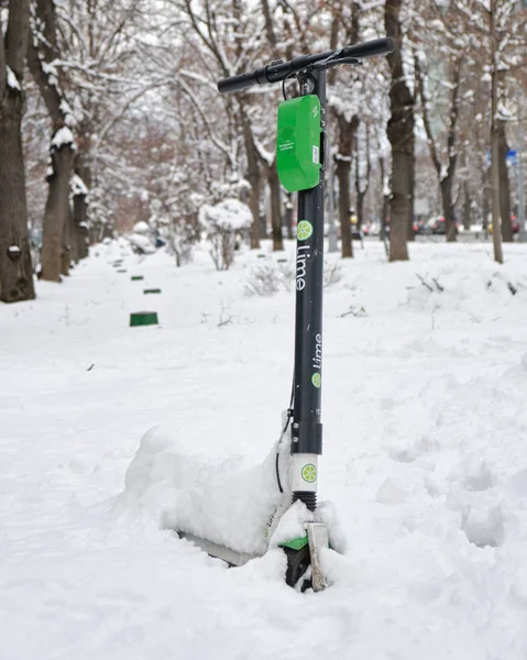 Jeden elektrický skútr Lime-S zaparkovaný ve sněhu, během zimy. — Stock fotografie