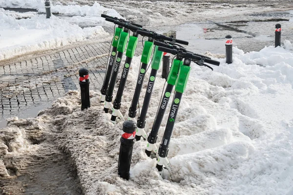 Scooters eléctricos Lime-S estacionados, de la compañía Lime (Neutron Holdings Inc.), cubiertos de nieve después de una tormenta de nieve durante un invierno suave en Rumania . —  Fotos de Stock