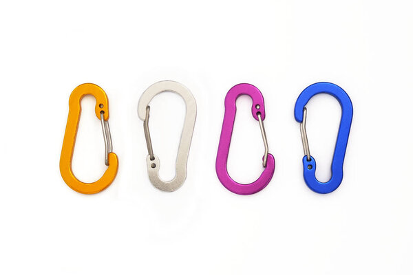 Четыре маленьких проволочных карабина используются не для скалолазания, а для подвешивания аксессуаров или ключей. Красочные карабины изолированы на белом фоне - вид сверху вниз
.