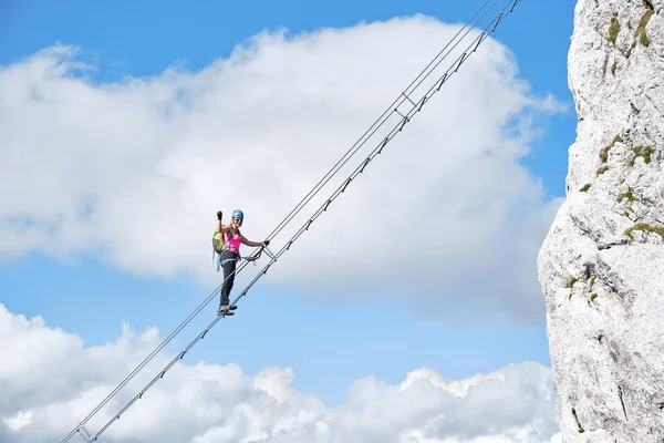 Avusturya 'daki Intersport Klettersteig Donnerkogel rotasındaki ferrata merdiveninde elini sıkıca tutan bir kadın tırmanıcı ile cennete giden merdiven..