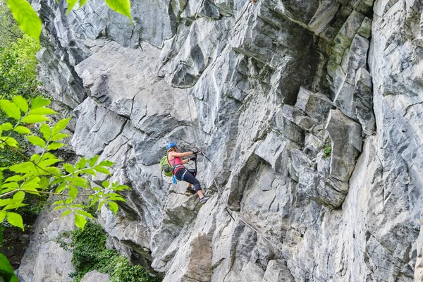 Woman climbing impressive overhanging rock formations on a via ferrata route called Zimmereben (rated D/E - difficult), near Mayrhofen, Zillertal valley, Austria.