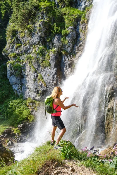 Woman hiker touching water drops at Dalfazer waterfall, Austria.
