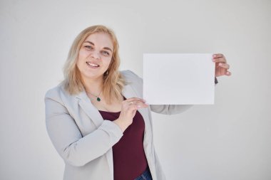 Şişman sarışın kız yazının altında beyaz bir çarşaf tutuyor.