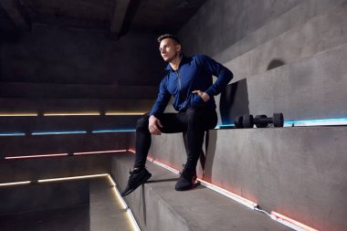 Adam neon ışıklarının arka planında dambıllarla antrenman yapıyor.