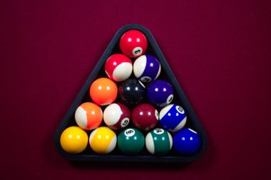 Renkli ve numaralı, çizgili ve sert bilardo topları siyah top rafında kırmızı keçeli bilardo masasında.