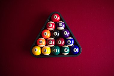 Siyah top rafında kırmızı keçeli bilardo masasında numaralandırılmış, renkli ve sert bilardo topları..