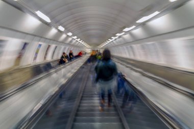 Subway passengers on escalators. Motion blur.