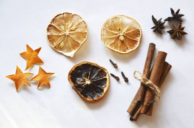 Various dry ingredients: cinnamon, dry lemon slices, clove seasoning, anise stars on a white background. Photo image.