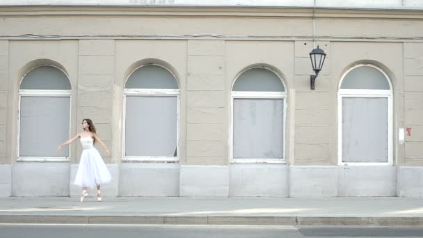Ballerina danser mot bakgrund av en färgglad byggnad och bilar förbi henne — Stockvideo