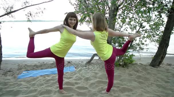 Jonge vrouwen beoefenen van yoga op het zand — Stockvideo