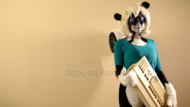 Girl dressed in a skunk costume is standing near the wall with a old keyboard — Stock Video