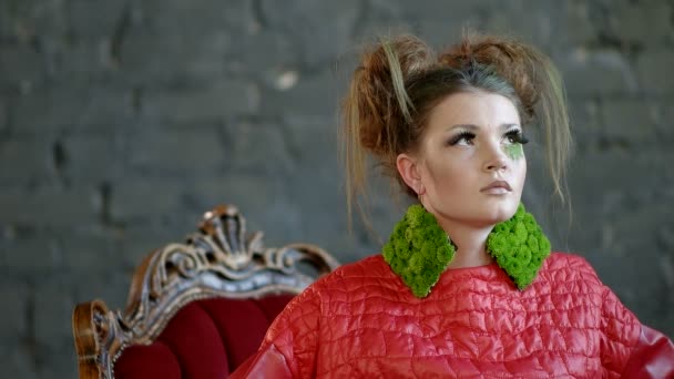 Голова и плечи модной девушки с макияжем, сидящей в красном кресле — стоковое видео