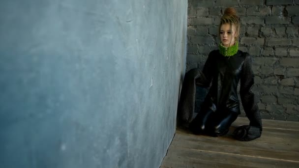Model-Frau in schwarzer Kleidung sitzt in einer Ecke — Stockvideo