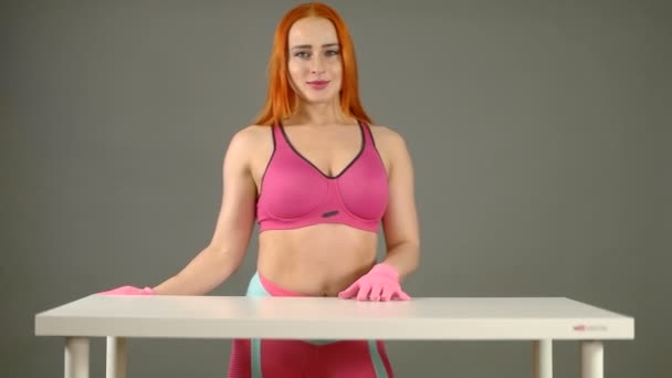 Uma menina de luvas rosa limpa uma mesa branca com as mãos — Vídeo de Stock