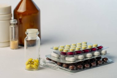 Beyaz arka planda kabarcıklar, şişeler, ampuller ve kavanozlardaki farklı ilaçlar