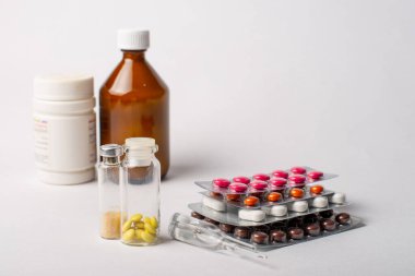 Beyaz arka planda kabarcıklar, şişeler, ampuller ve kavanozlardaki farklı ilaçlar