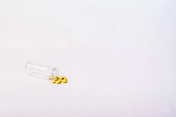 Compresse gialle di valeriana rovesciate da una piccola bottiglia di vetro. Isolato su uno sfondo bianco. Concetto farmaceutico . — Foto Stock