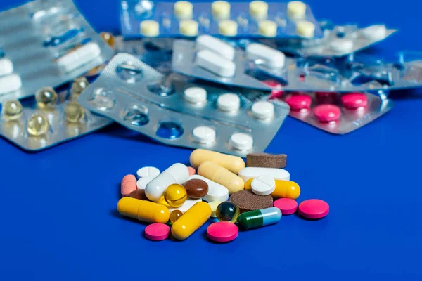Primo piano di pillole multicolori assortiti su uno sfondo blu. Medico piatto laici . — Foto Stock