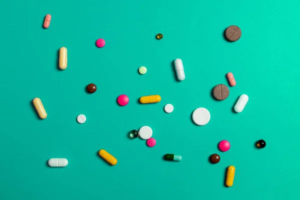 Primo piano di pillole multicolori assortiti su uno sfondo verde. Medico piatto laici . — Foto Stock