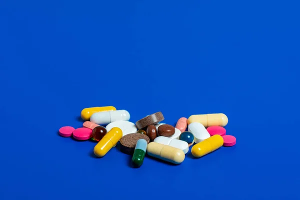 Primo piano di varie pillole multicolori su un aereo blu. Posata piatta medica. Isolato su sfondo blu . — Foto Stock